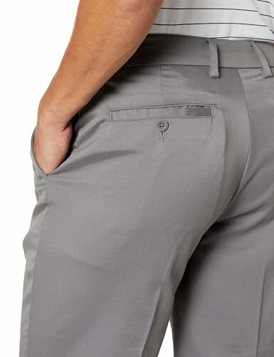 Person wearing grey trousers with a back pocket.