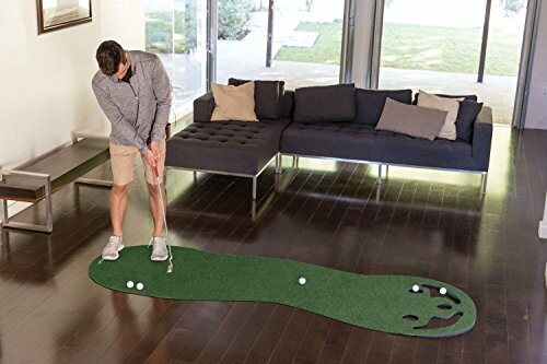 Man practicing golf on an indoor putting mat in a living room.