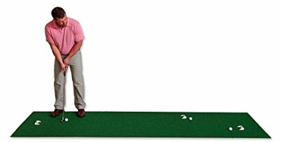 Man practicing putting on a green mat with golf balls.