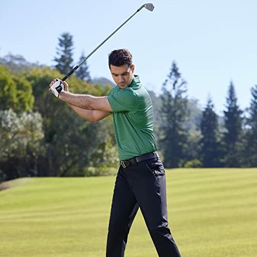 Man in green shirt swinging a golf club on a golf course